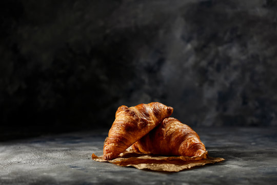 Fresh tasty croissants on dark background and free space for your decoration. 