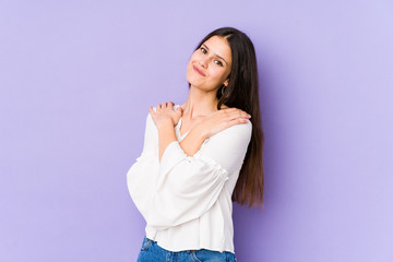 Obraz premium Young caucasian woman isolated on purple background hugs, smiling carefree and happy.