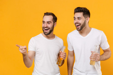 Cheerful young men guys friends in white empty blank t-shirts posing isolated on yellow orange...