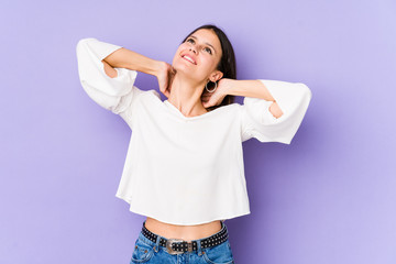 Young caucasian woman isolated on purple background feeling confident, with hands behind the head.