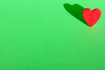 Red heart with shadow on green background for copy space, holiday postcard, Mothers day, Valentines day and love.