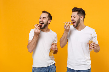Cheerful young men guys friends in white blank empty t-shirts posing isolated on yellow orange...