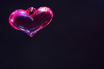 Colorful plastic heart photographed on mirror surface in studio