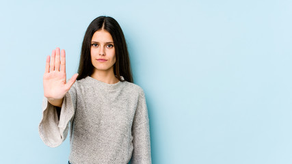 Young caucasian woman isolated on blue background standing with outstretched hand showing stop...