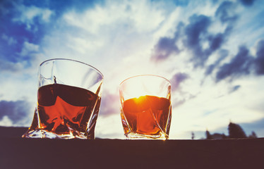 shot of whiskey at sunset dramatic sky on mountain landscape background