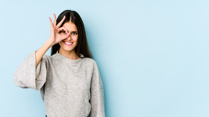 Young caucasian woman isolated on blue background excited keeping ok gesture on eye.