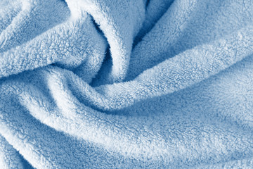 Fluffy classic blue towel background, close-up. Gentle baby pastel fabric with waves and folds....