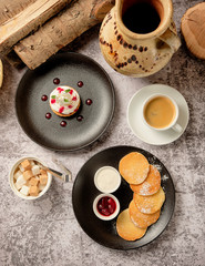Cupcakes with whipped white vanila cream with pancakes and berry jam, a cup of black coffee americano for breakfast, background. Food and drink concept.