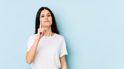 Young caucasian woman isolated on blue background showing number one with finger.