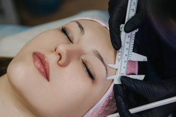Girl's face with closed eyes macro shot. The master with a black gloved hand holds a cosmetic...