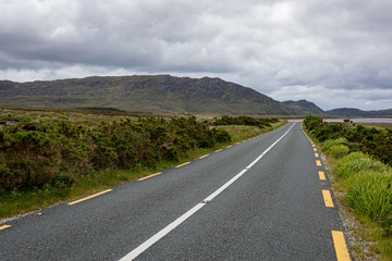 Irish road through the hills under cloudy sky
