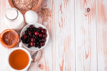 Delicious, healthy, hearty breakfast on the white table. Eggs, oatmeal, milk, tea, banana toast, homemade salted caramel, pancakes with fruit, orange juice.