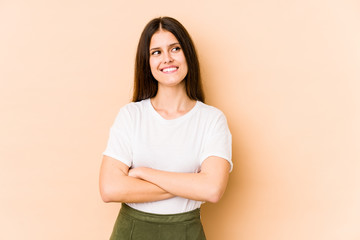 Obraz premium Young caucasian woman isolated on beige background smiling confident with crossed arms.