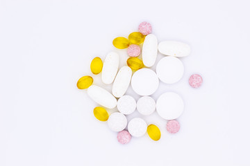 Different vitamins, pills and capsules on a white background.