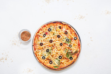 Pizza with olives on a white background, decorated with tomatoes and mushrooms. The concept of ingredients for making pizza.