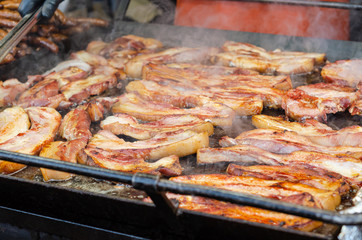 Street food, cooking pork steaks and sausages on grill