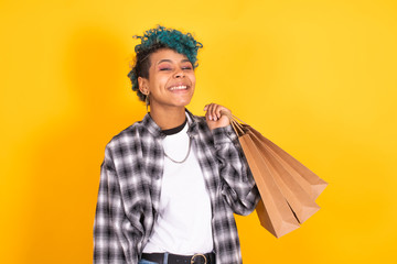 young brunette girl with shopping bags isolated on yellow background