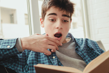 young teenage boy reading or studying at home