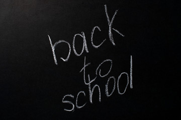 back to school written in white chalk on a black chalkboard