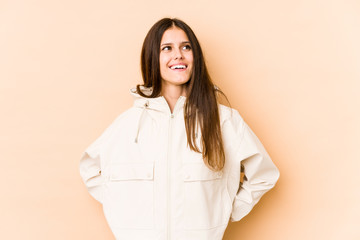 Young caucasian woman isolated on beige background relaxed and happy laughing, neck stretched showing teeth.