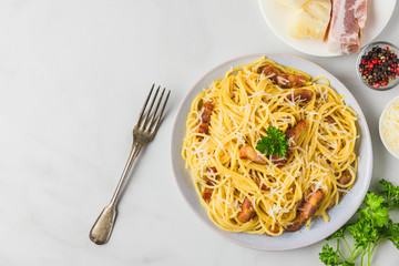 Classic homemade italian pasta carbonara with bacon, eggs, parmesan cheese and parsley in a plate with fork. top view