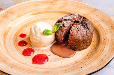 Hot Chocolate Souffle with vanilla ice cream and raspberry sauce. Classic French dessert. Chocolate fondant lava cake with custard and mint, close up
