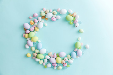 Happy Easter concept. Preparation for holiday. Easter candy chocolate eggs and jellybean sweets isolated on trendy pastel blue background. Simple minimalism flat lay top view copy space.