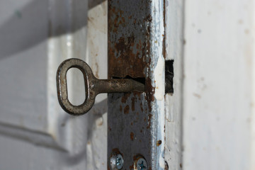 Old key in the door lock closeup.