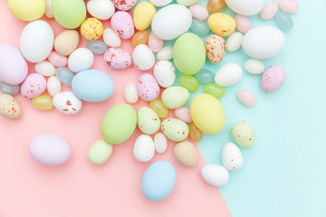 Happy Easter concept. Preparation for holiday. Easter candy chocolate eggs and jellybean sweets isolated on trendy pastel blue pink background. Simple minimalism flat lay top view copy space.