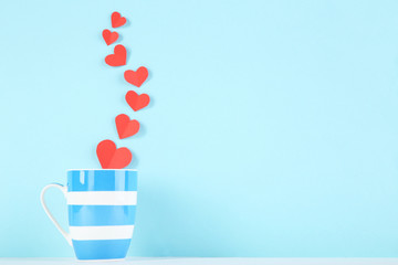 Paper hearts with cup on blue background