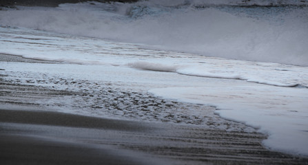 Fototapeta na wymiar A sea wave rolls over the sandy beach