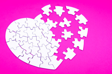 Heart rendered into white puzzle pieces on pink background