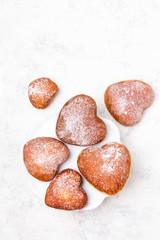 Homemade heart sheped donuts with powdered sugar on white background. Tasty doughnuts, copy space