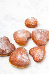 Homemade heart sheped donuts with powdered sugar on white background. Tasty doughnuts, copy space