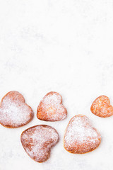 Homemade heart sheped donuts with powdered sugar on white background. Tasty doughnuts, copy space