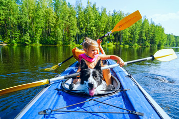 A girl with a dog sitting in a kayak on the lake .