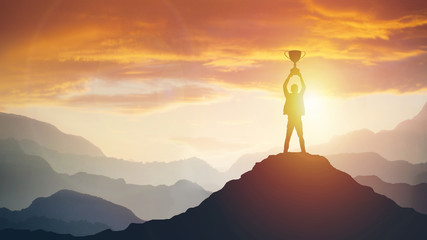 Silhouette of a man holding a trophy at sunset