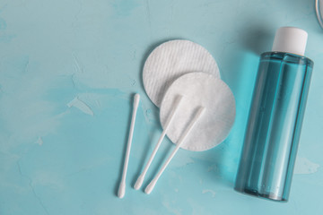 blue micellar water, cotton pads and sticks on a concrete background. With copy space