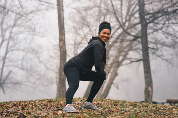 Fototapeta premium A young African American woman stretching legs outdoors.