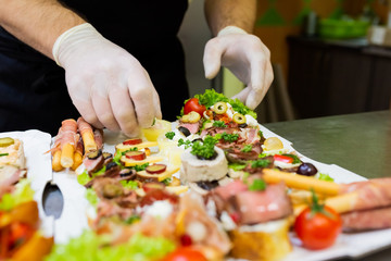 Chef preparing fresh finger food on paper plate for delivery.