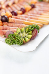 Close up of bread sticks grissini with prosciutto ham served on table.