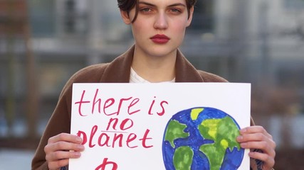 Close up portrait of a young girl student with a poster with the inscription - This is no Planet B. Climate strike