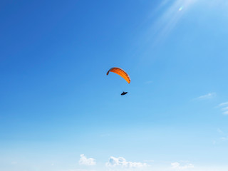 Alone paraglider flying in the blue sky against the background of clouds. Paragliding in the sky on a sunny day.