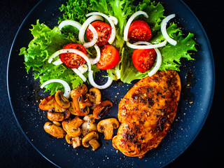 Roast chicken breast and vegetables on wooden background