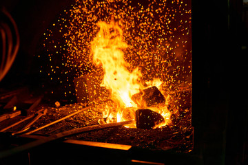 blacksmith furnace with burning fire and forging tools lying nearby