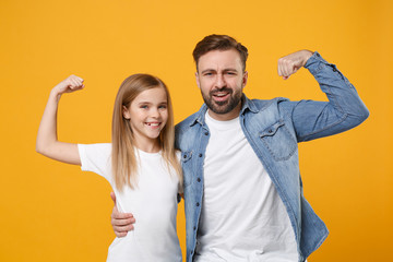 Strong bearded man in casual clothes have fun with cute child baby girl. Father little kid daughter isolated on yellow background. Love family day parenthood childhood concept. Showing biceps muscles.
