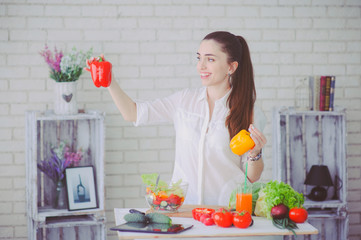 Pretty girl preparing fresh vegetable salad in her kitchen