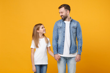 Obraz premium Bearded man in casual clothes have fun with child baby girl. Father little kid daughter isolated on yellow background. Love family day parenthood childhood concept Holding hands looking at each other.