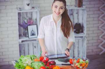 Pretty girl preparing fresh vegetable salad in her kitchen