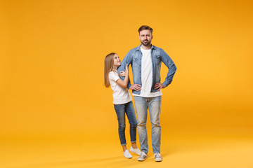 Bearded man in casual clothes with child baby girl. Father little kid daughter isolated on yellow background. Love family parenthood childhood concept. Stand with arms akimbo on waist holding hands.